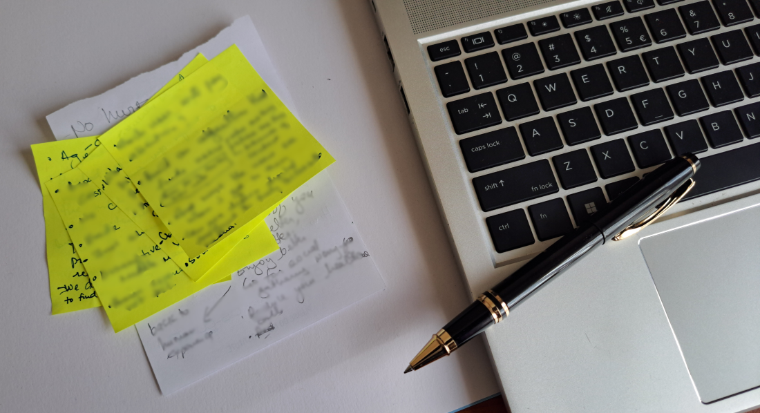 A computer, sticky notes and a pen depicting the process of clinician advisory-assisted travel planning.