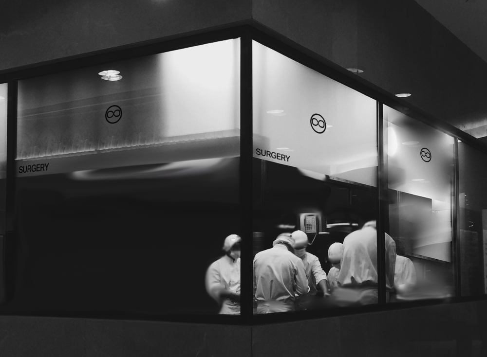 A surgery seen through its corner windows at night, the ABCDEFGHUMAN mark on the glass