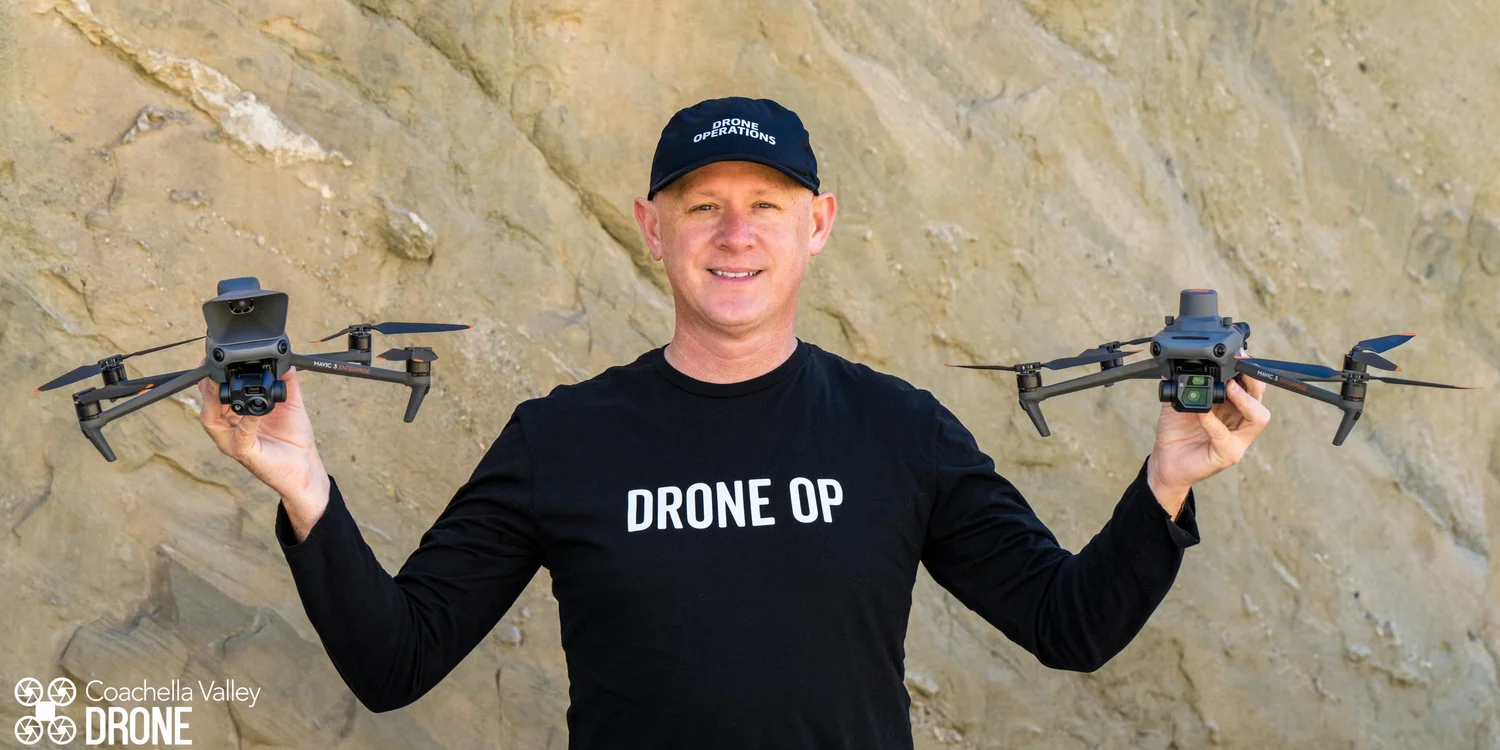James holding two DJI drones in front of a desert rock face