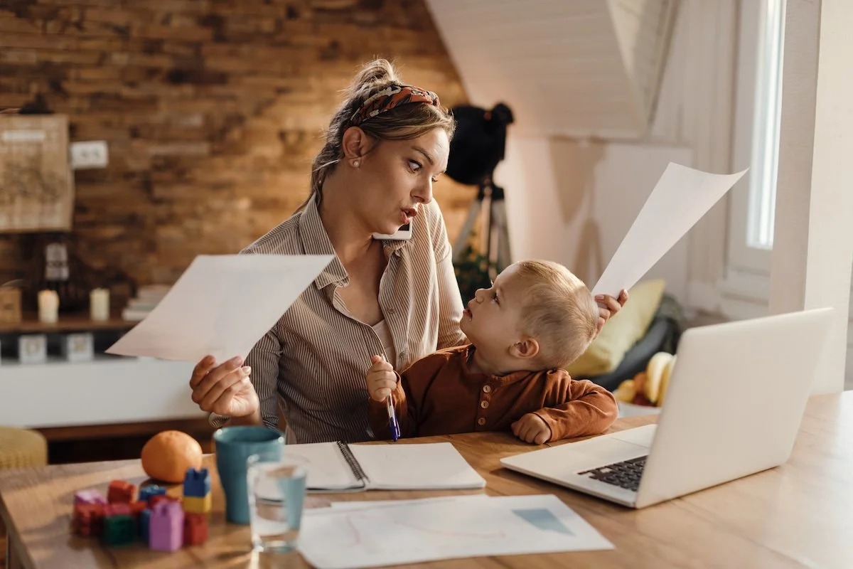 Mother applying for a job on laptop with child nearby