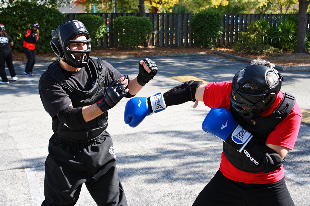 Adult students practice controlled martial arts sparring outdoors