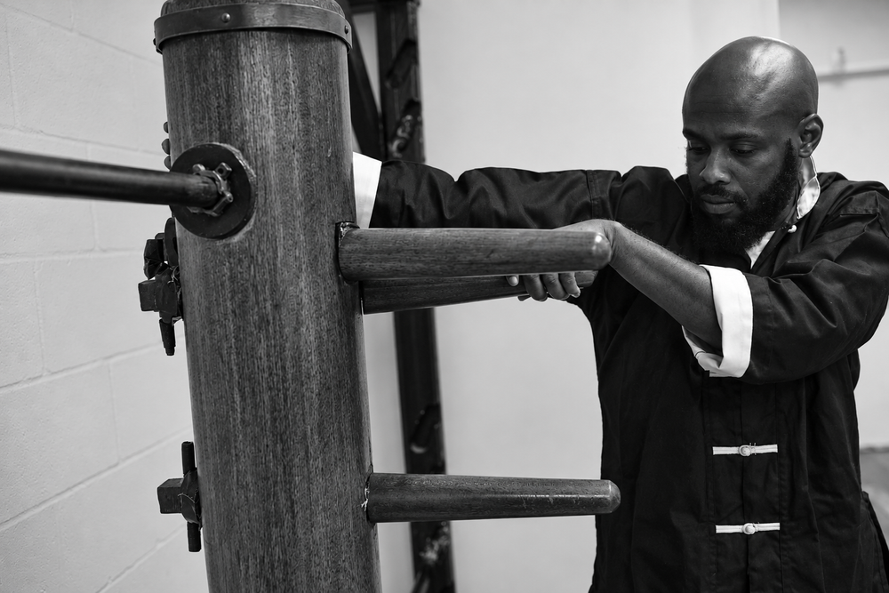 Wing Chun practitioner works a wooden dummy in monochrome