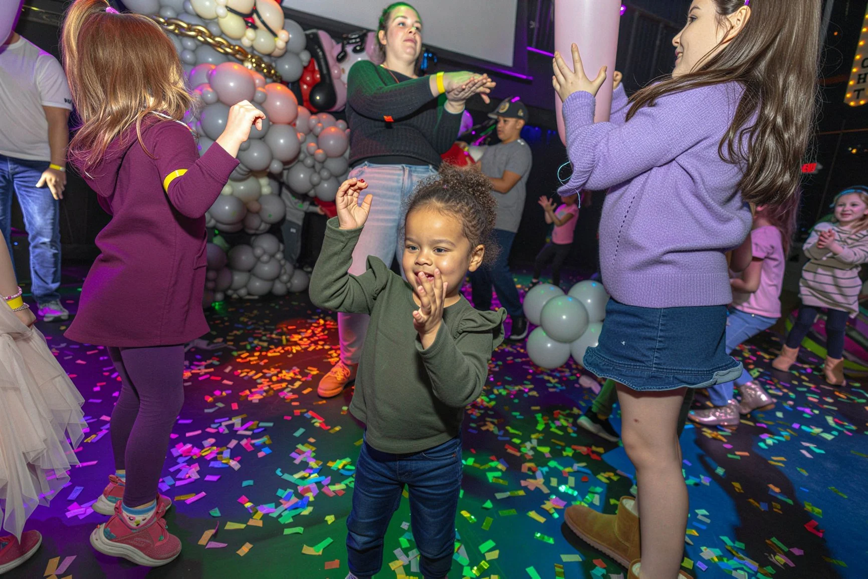 A toddler dancing and clapping on a confetti-covered dance floor at Fam Jam