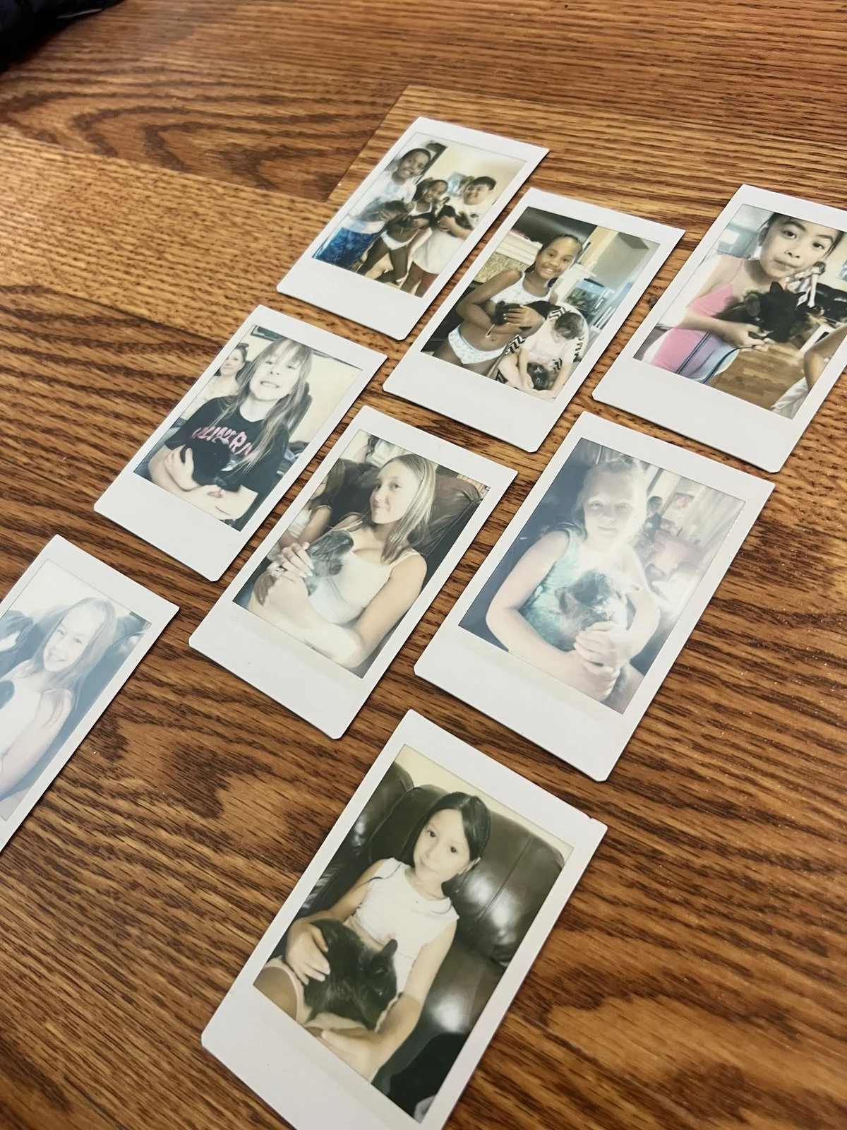 Instant photographs of smiling party guests cuddling bunnies, spread across a wooden table