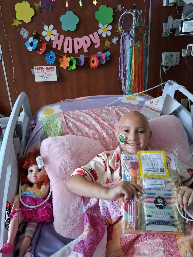 Annie smiling in her hospital bed with activities and toys