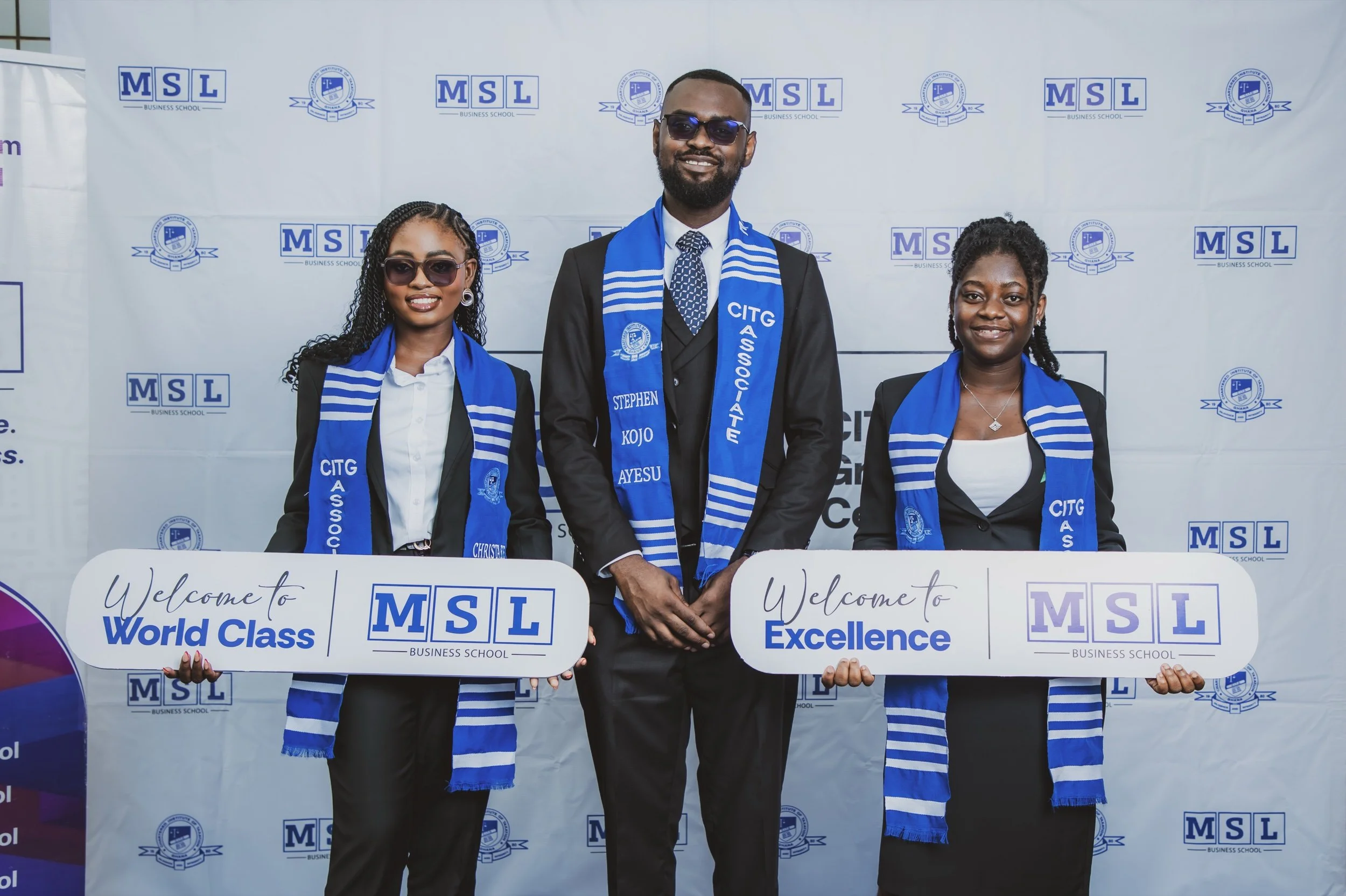 Three smiling MSL Chartered Tax Practitioners wearing CITG scarves and holding Welcome to World Class and Welcome to Excellence placards in front of an MSL and CITG backdrop
