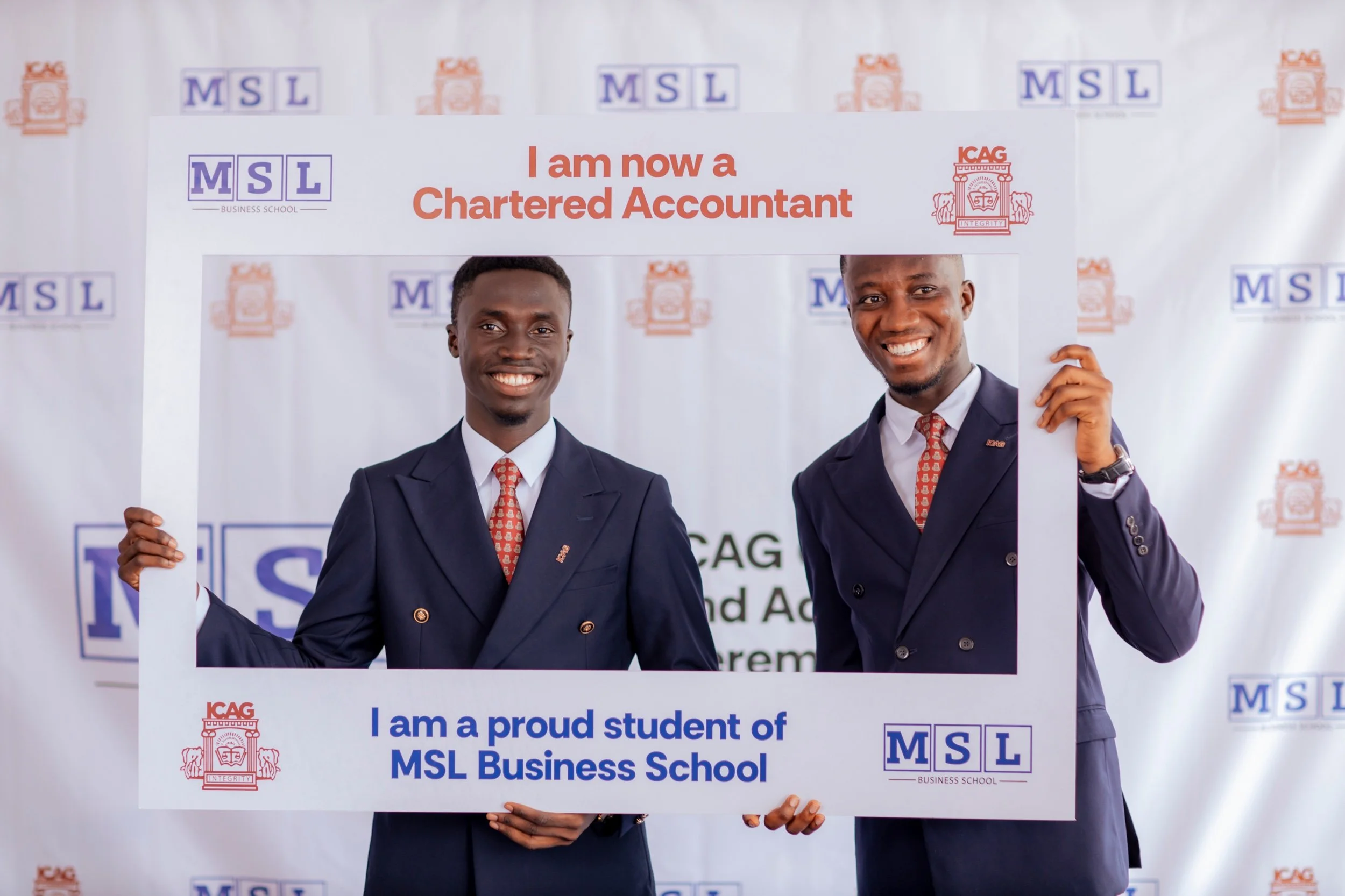 Two smiling MSL Chartered Accountants holding an MSL and ICAG achievement frame in front of an MSL and ICAG backdrop
