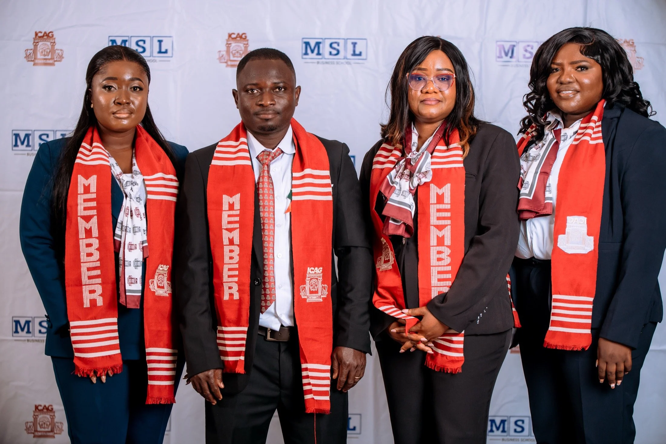 Four MSL Chartered Accountants wearing their ICAG membership stoles in front of an MSL and ICAG backdrop