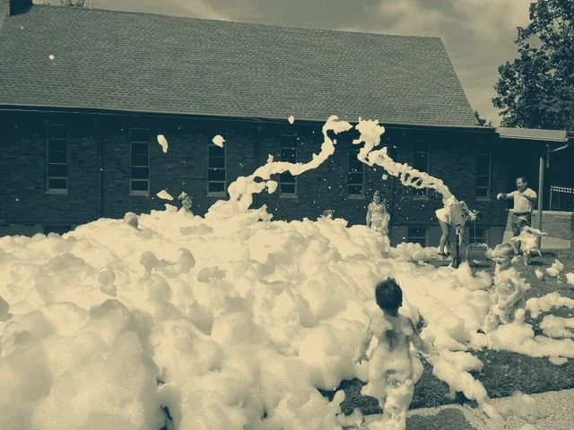 Kids running through a foam party outside the church