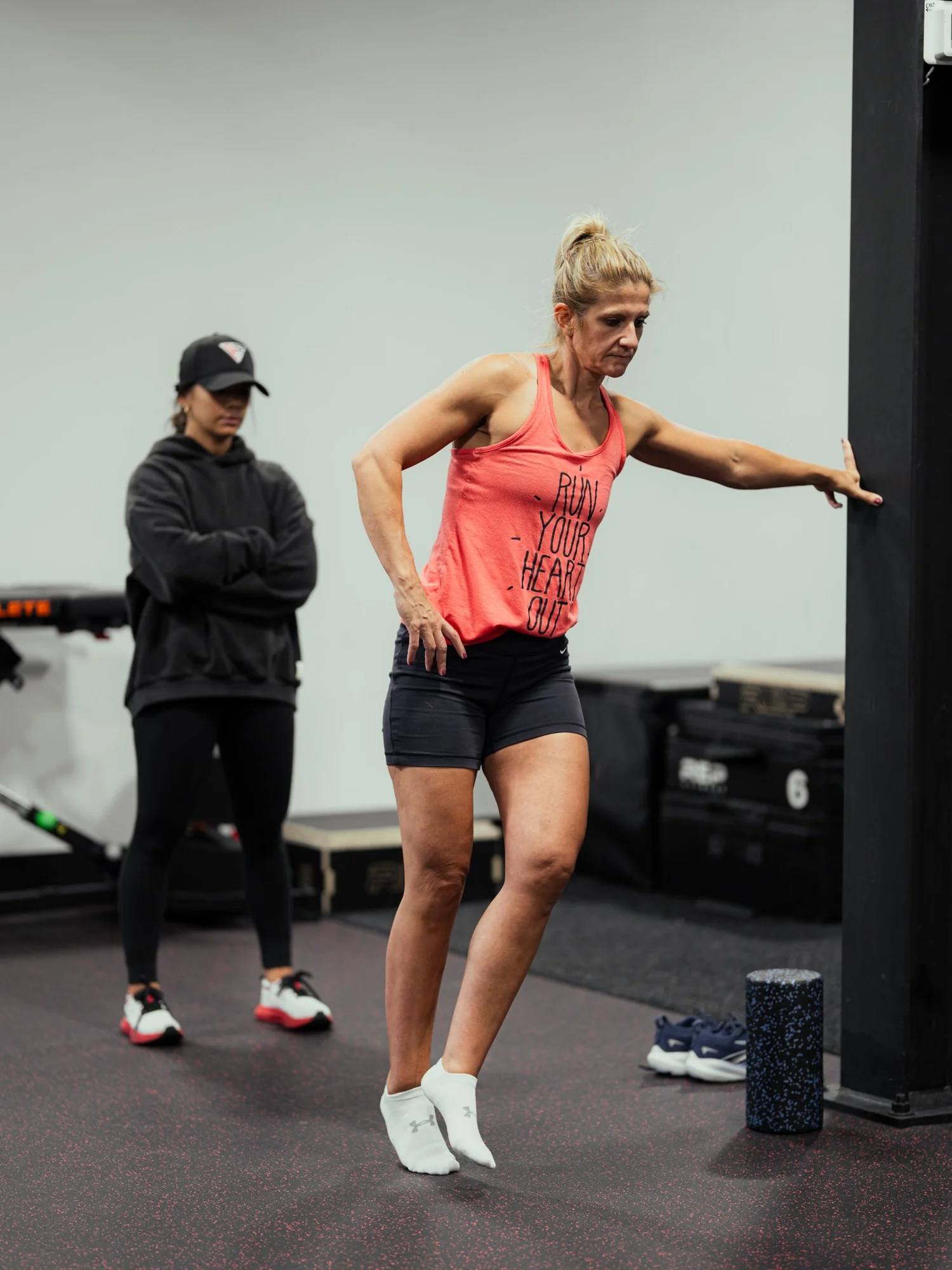 Runner in a running shirt doing a calf raise during a running injury rehab session