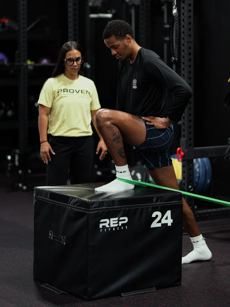 Clinician coaching an athlete through a banded box step-up