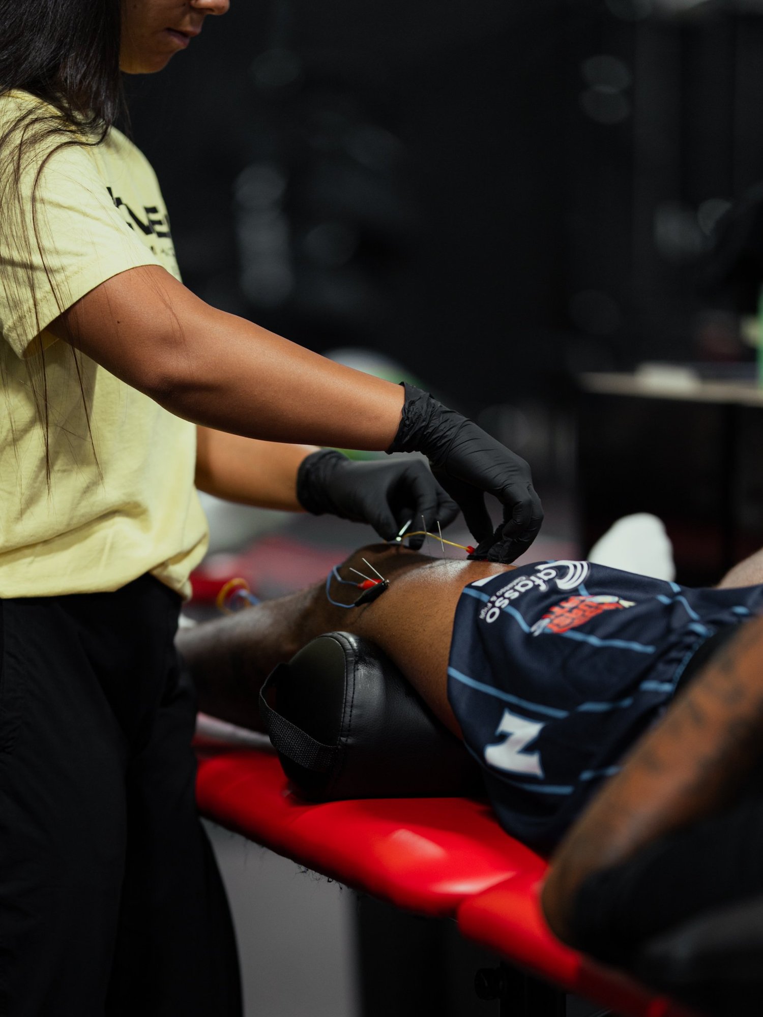 Proven clinician performing dry needling with electrical stimulation on an athlete’s leg