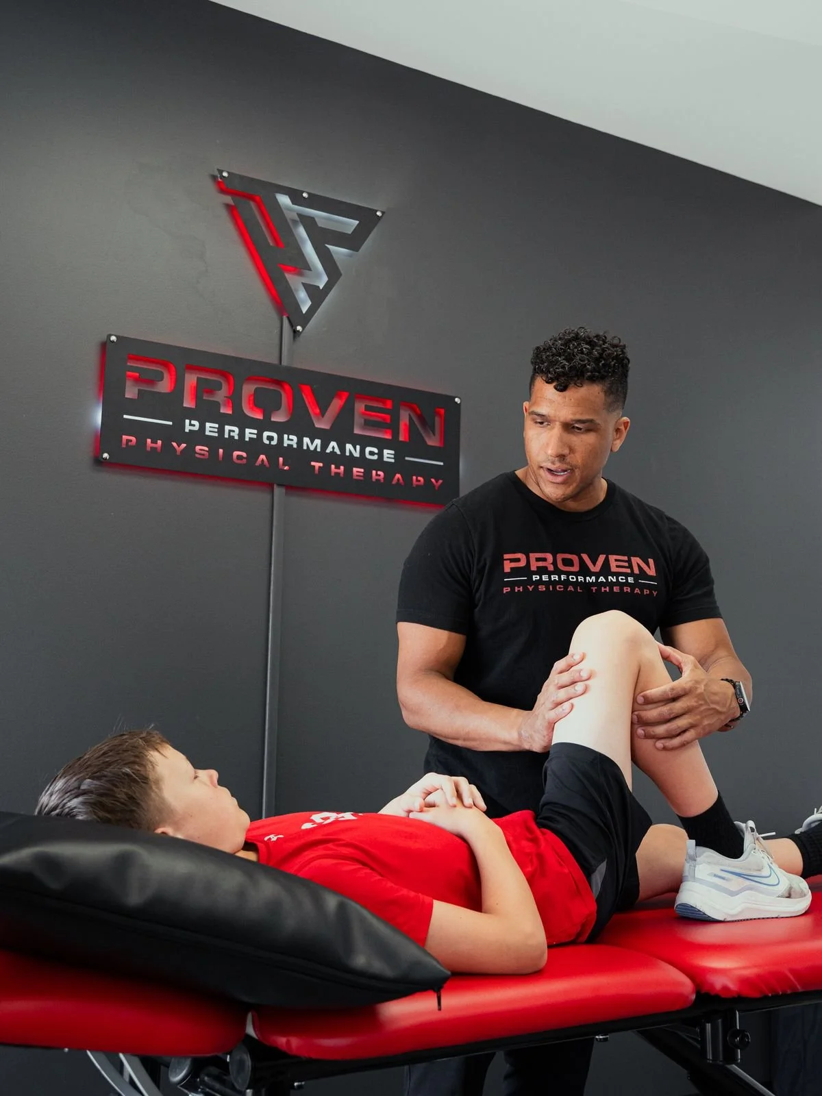 Proven clinician assessing a young athlete’s knee on the treatment table