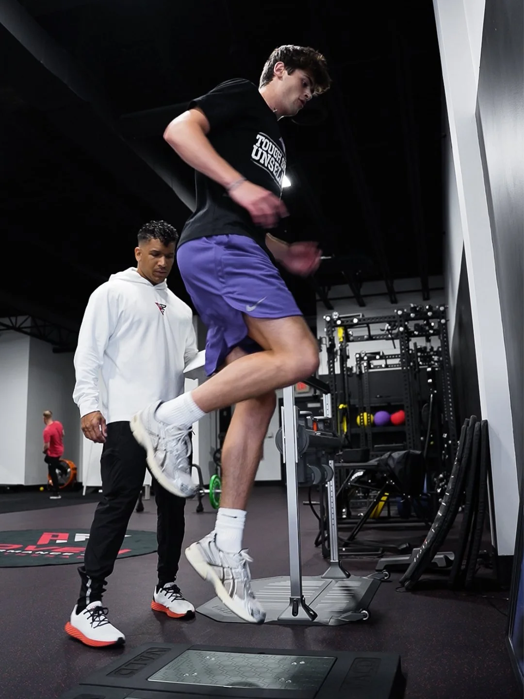 Athlete performing a single-leg hop test on VALD force plates while a Proven clinician watches