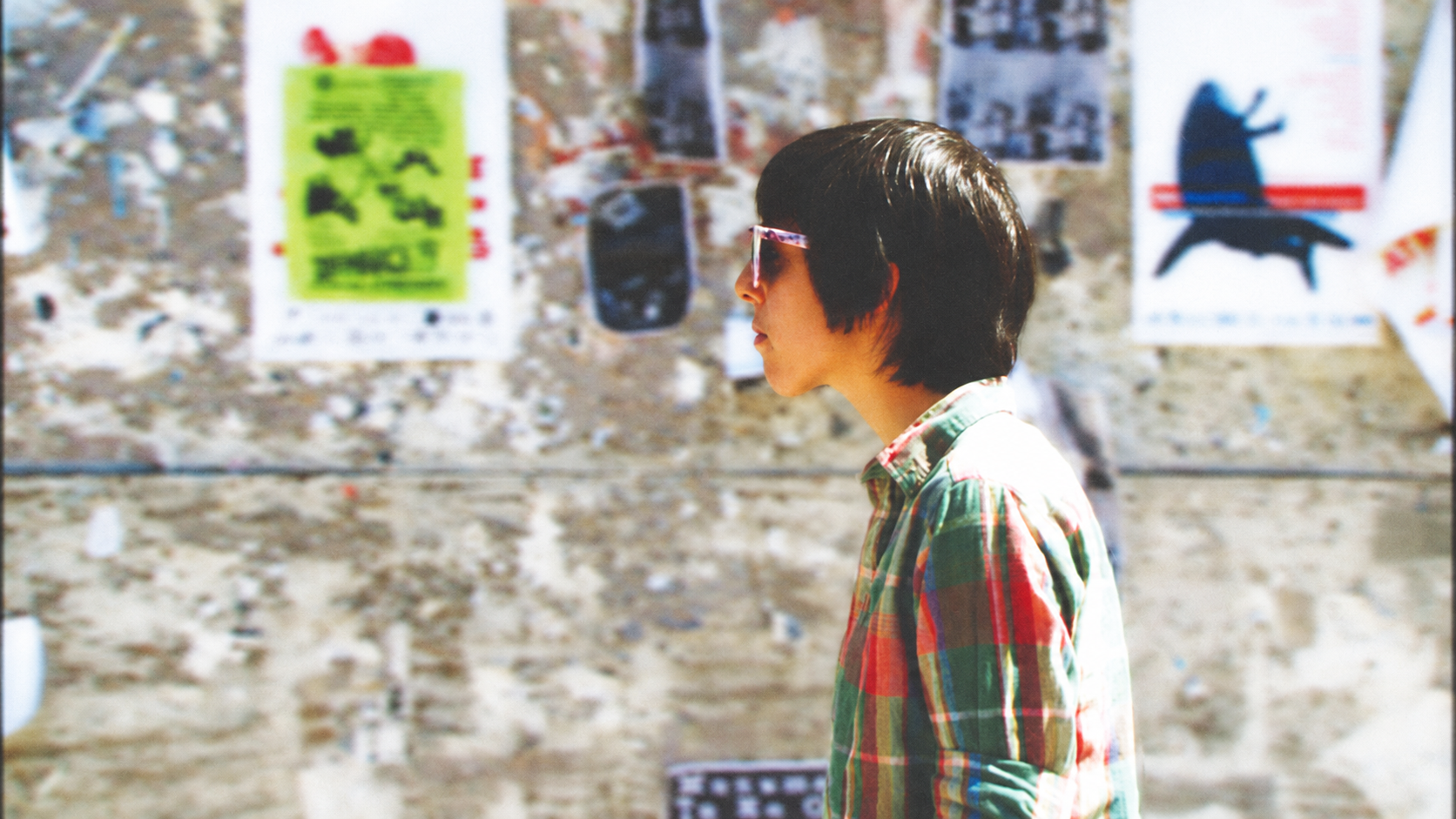 Austin musician beside a wall of concert posters, with Echotone artwork