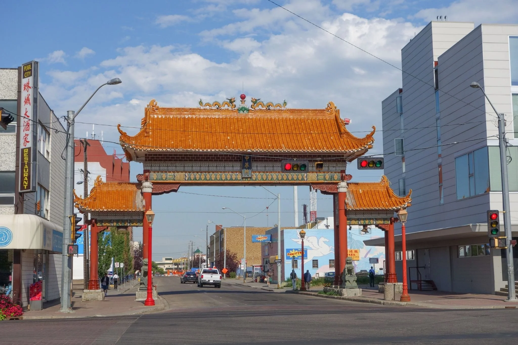 The Harbin Gate spanning 102 Avenue in Edmonton's Chinatown, with orange tiled roofs, red columns and guardian lions on stone bases