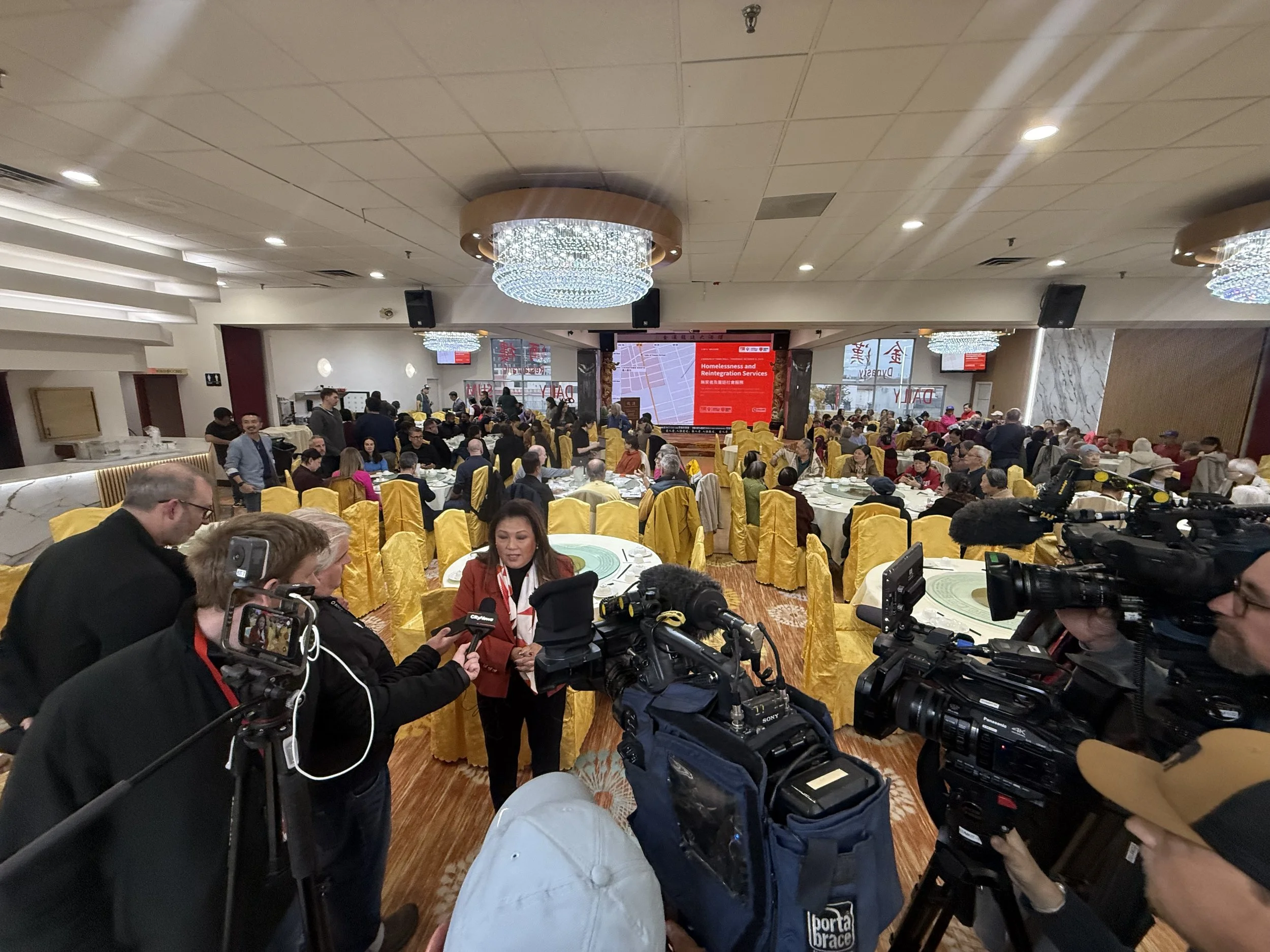 Community members and news crews at a Chinatown Safety Council event in an Edmonton Chinatown banquet hall
