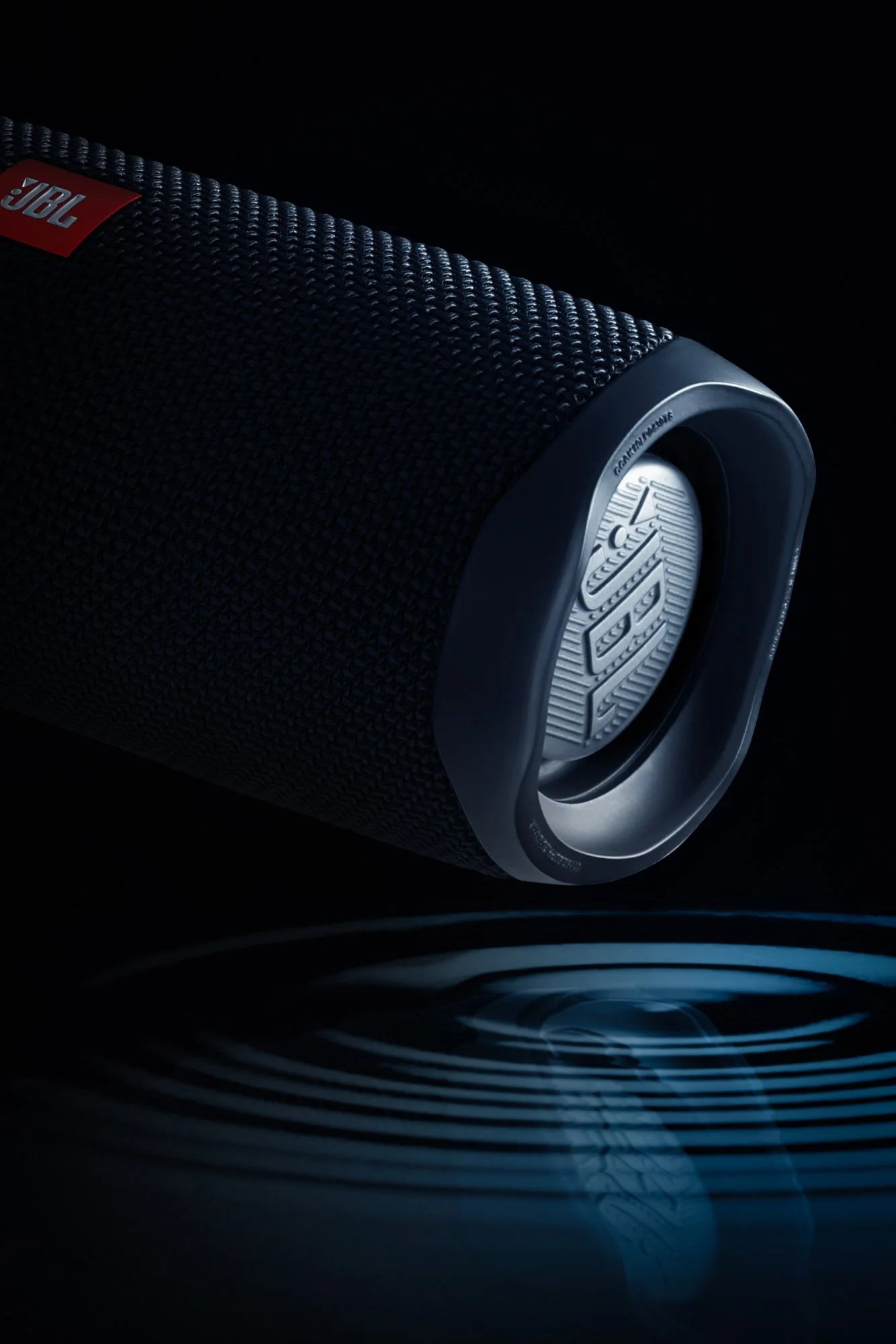 JBL Charge 4 — enceinte inclinée sur fond noir, reflet eau