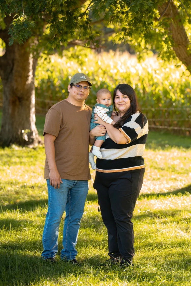 Parents and their baby standing together for an autumn family portrait at Poppy’s Pumpkin Patch.