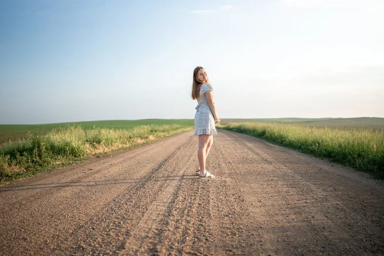 Bella looking back toward the camera on a quiet country road between fields