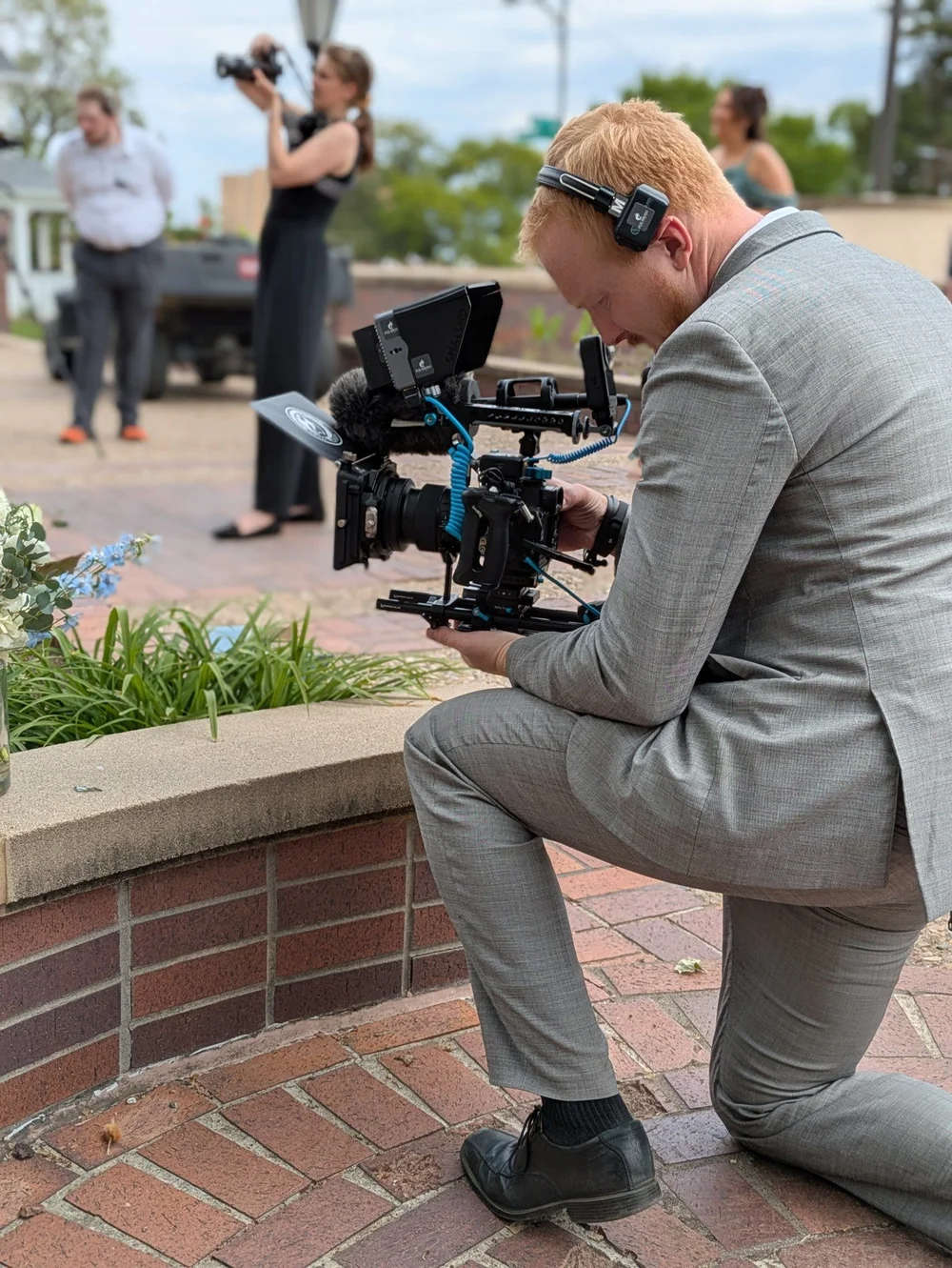 Trevor filming with a cinema camera while Hannah photographs in the background at Grace and Alex’s wedding.