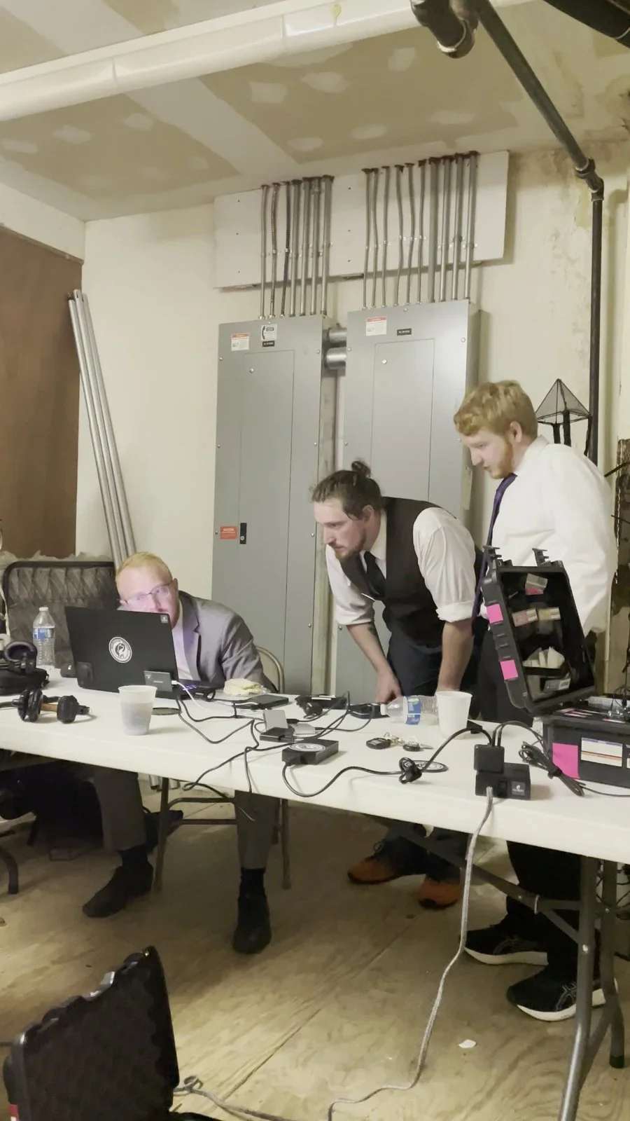 Three Fox Brush Films team members reviewing work together at a laptop beside their camera equipment.