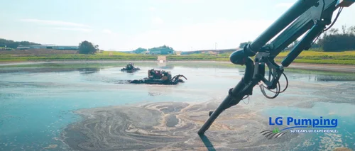 A pumping boom extends over a manure lagoon, with floating agitation equipment working in the background.