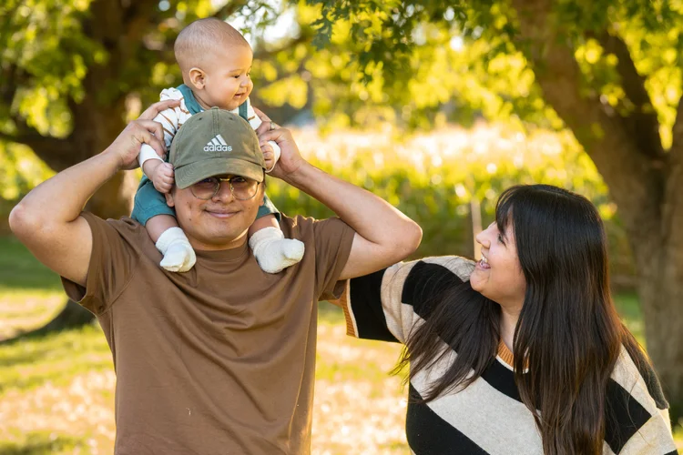 A baby riding on dad’s shoulders while mom looks up.