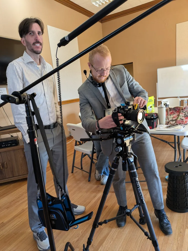 Two filmmakers checking a cinema camera and boom microphone during hands-on training.
