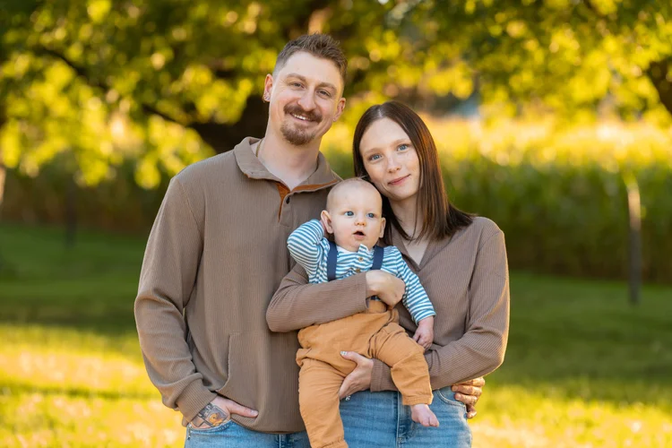 Parents holding their baby during a fall family mini session at Poppy’s Pumpkin Patch in Norfolk, Nebraska.