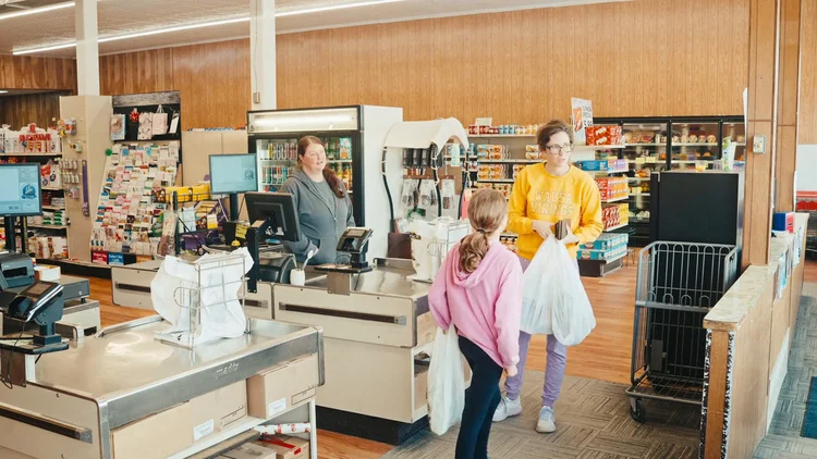 A cashier and shoppers at the checkout counters inside The Market in Wausa