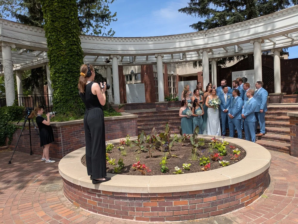 A Fox Brush Films photographer guiding Grace and Alex’s wedding party through outdoor portraits.