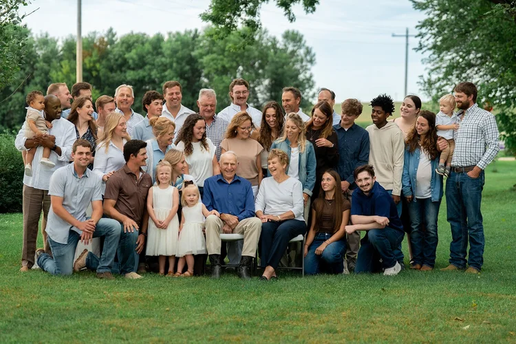 The extended Kumm family laughing together around seated grandparents.