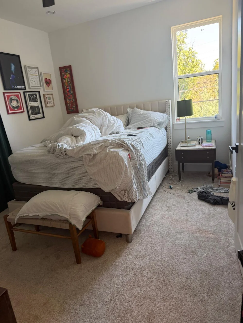 Before: unmade bed with clothes on the bench and floor in an Austin bedroom