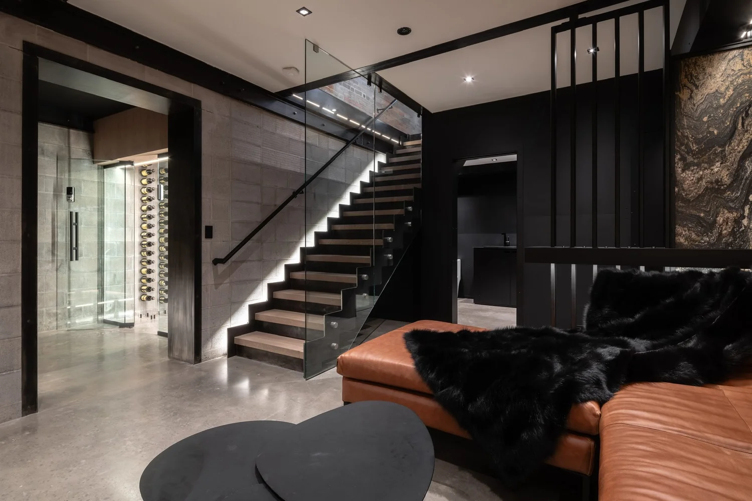 Floating blackened-steel stair with glass guard and steel-fin screen