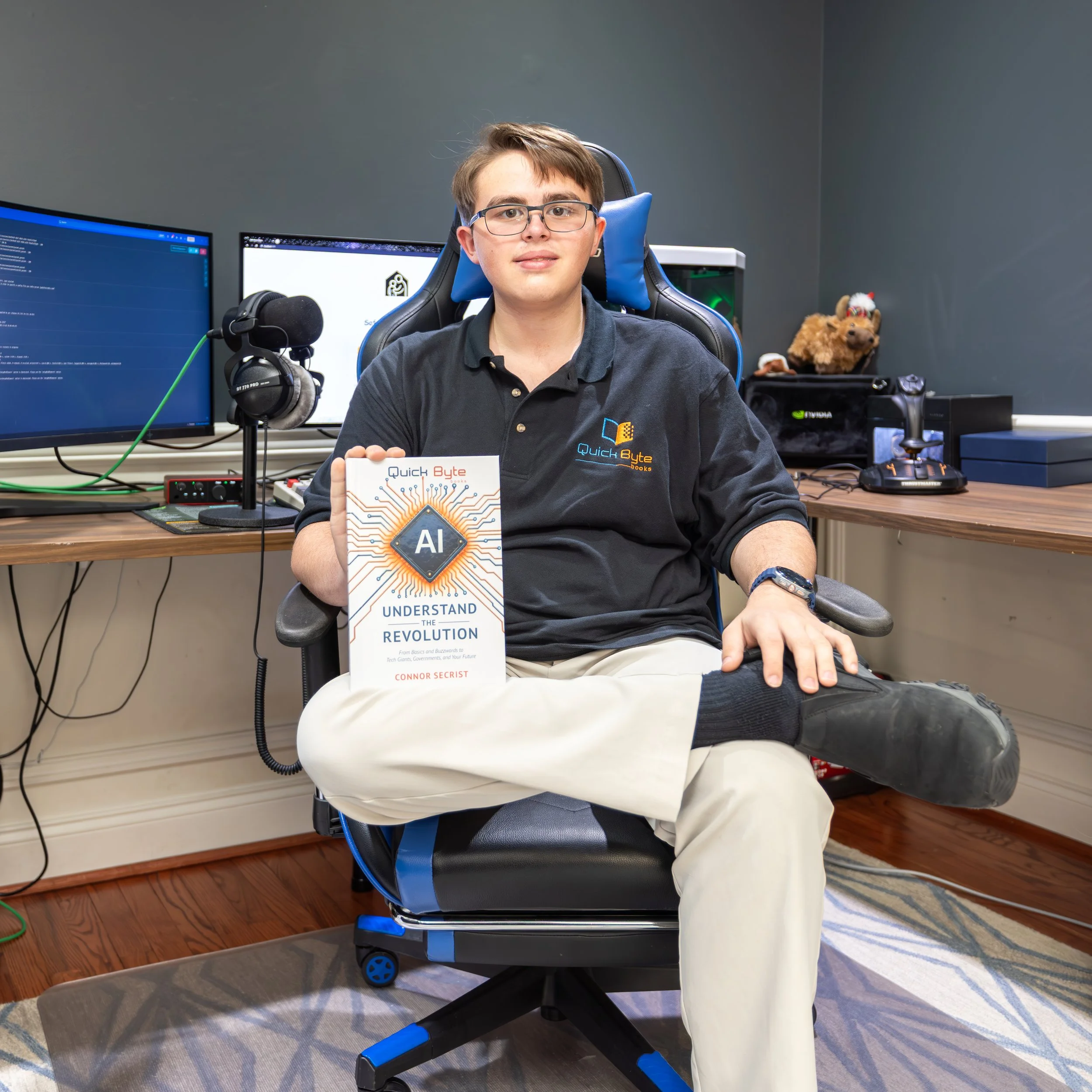 Teen author Connor Secrist sitting at his computer desk holding his book AI: Understand the Revolution