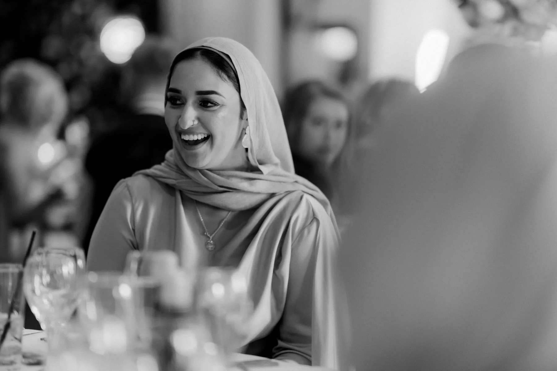A guest smiling during the speeches, photographed in black and white.