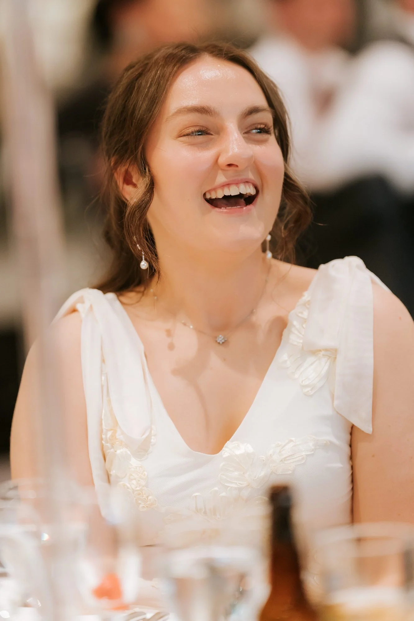 A young guest in a white dress laughing during the reception