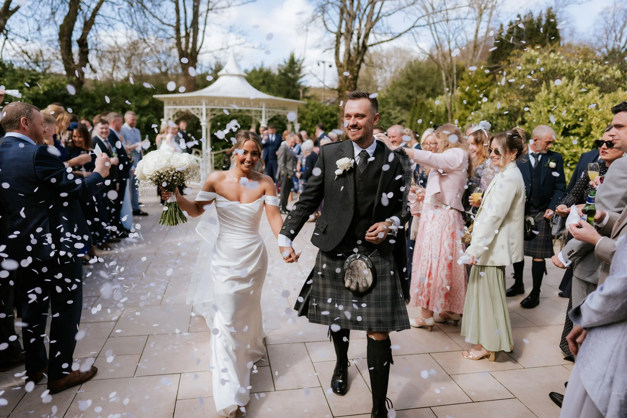 Elle and Adam smiling as guests shower them with confetti