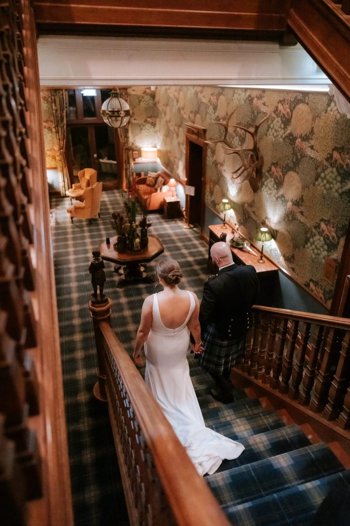 Kendall and Ewen walking down the tartan-carpeted staircase inside the hotel.