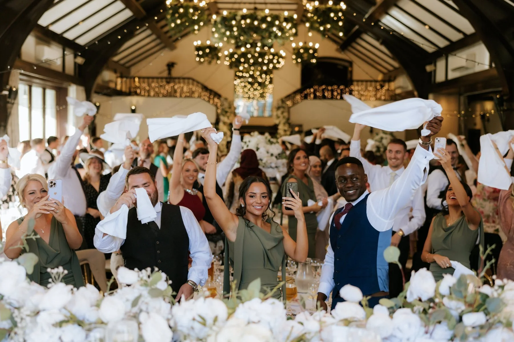 Wedding guests waving their napkins in the ballroom as the celebrations get going.