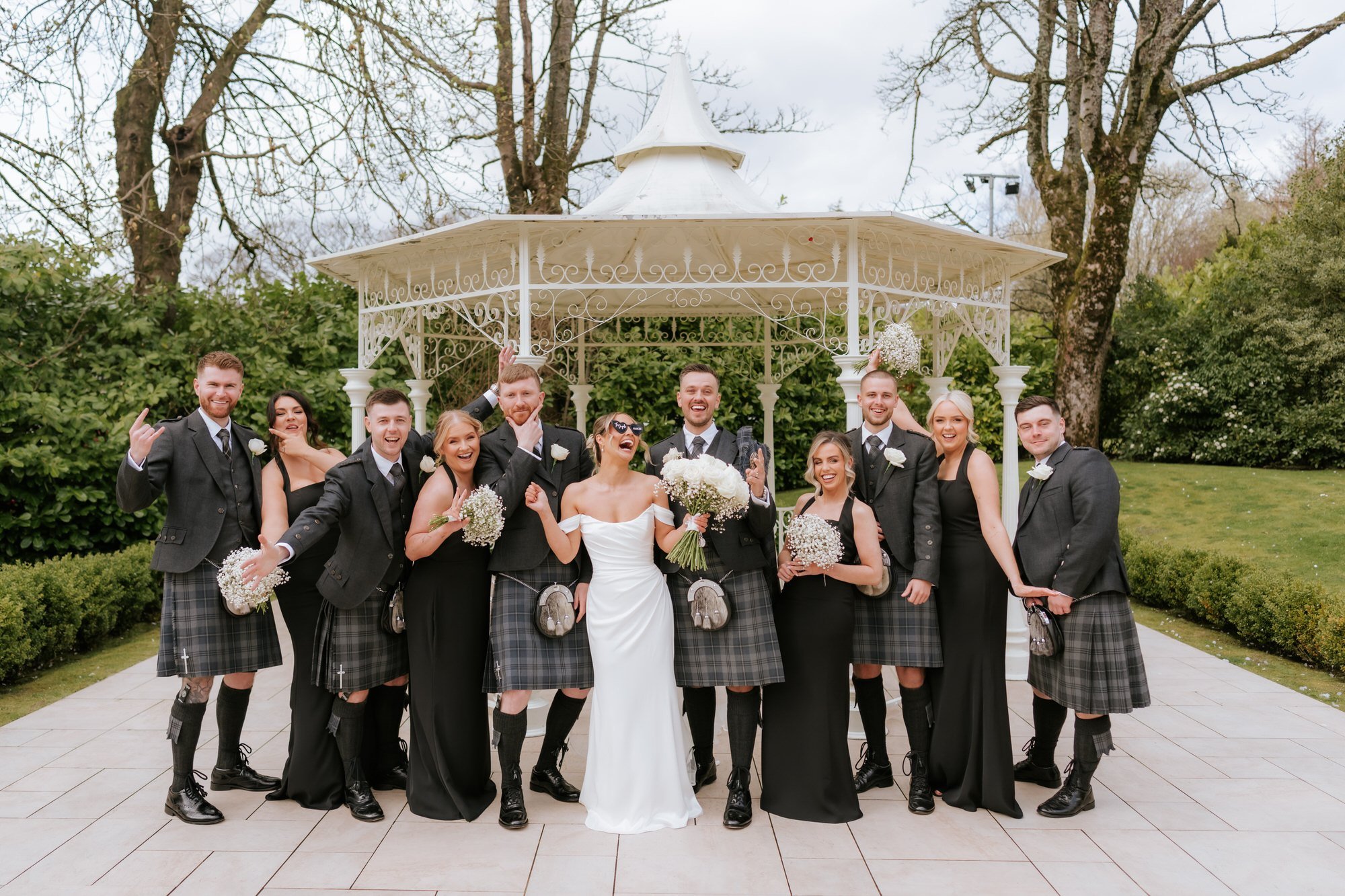 The wedding party cheering around Elle and Adam beside the gazebo
