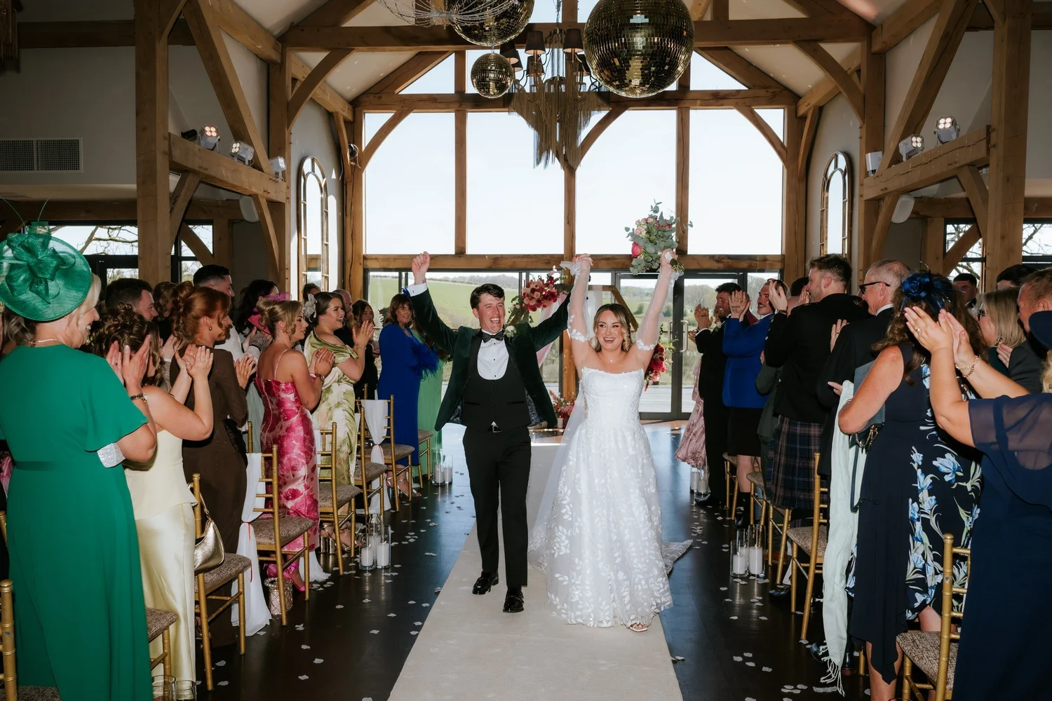 The newlyweds celebrating with their arms raised as they walk back up the aisle.