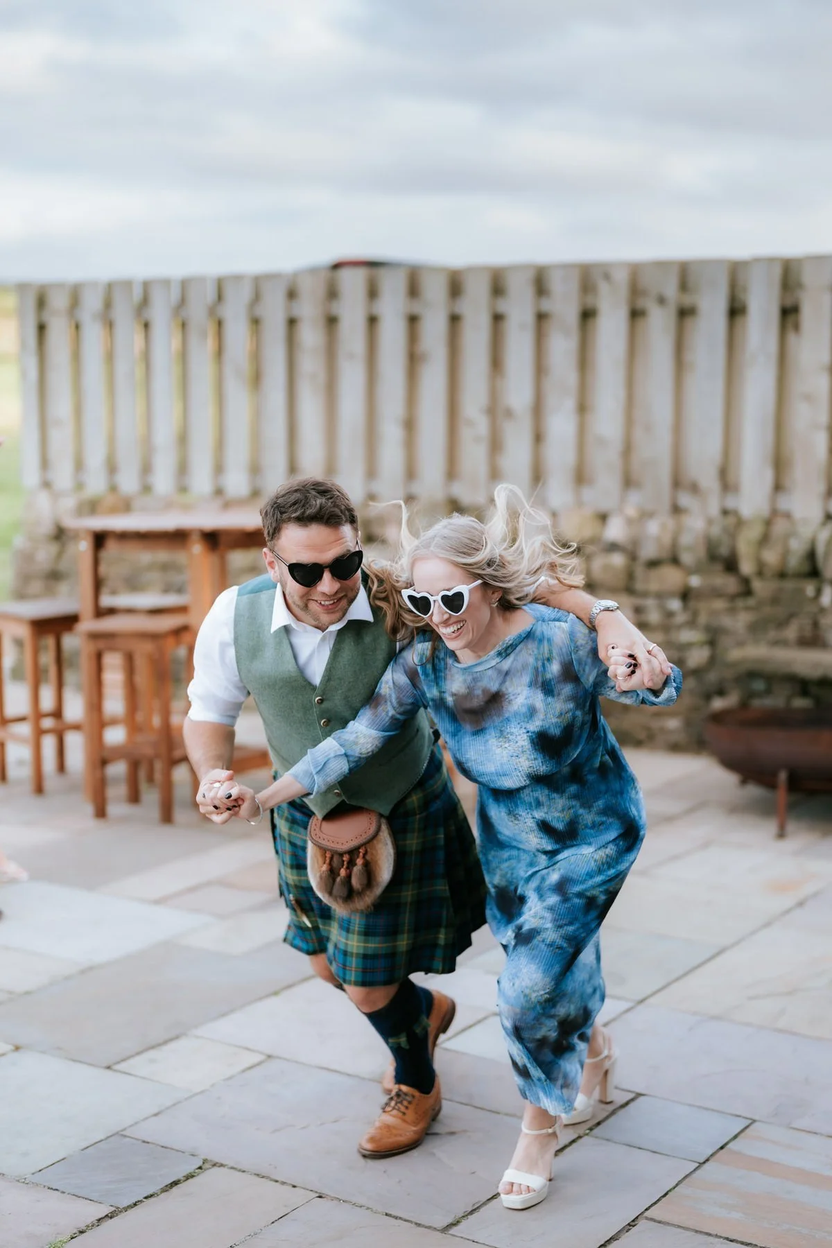 Wedding guests in sunglasses having a laugh together outside on the patio.