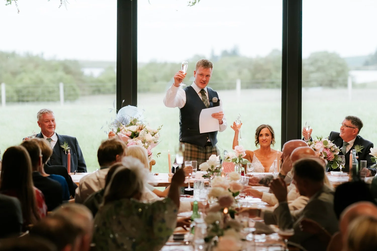 Jamie raising a glass as he gives his wedding speech beside Lauren.