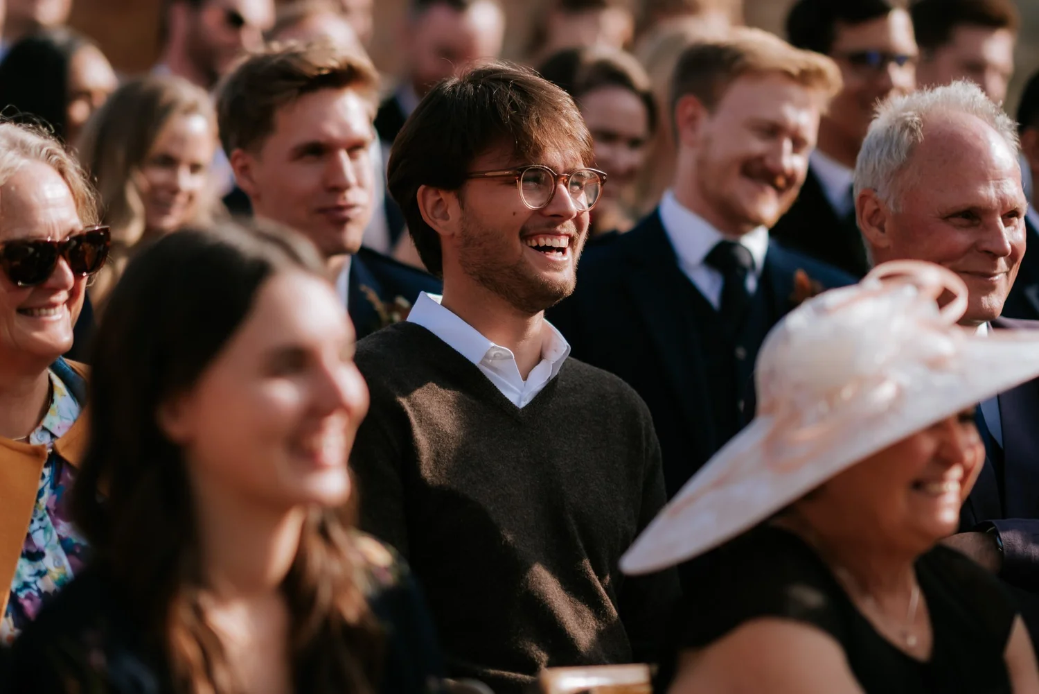 Guests watch the outdoor ceremony, with faces turned towards the couple.