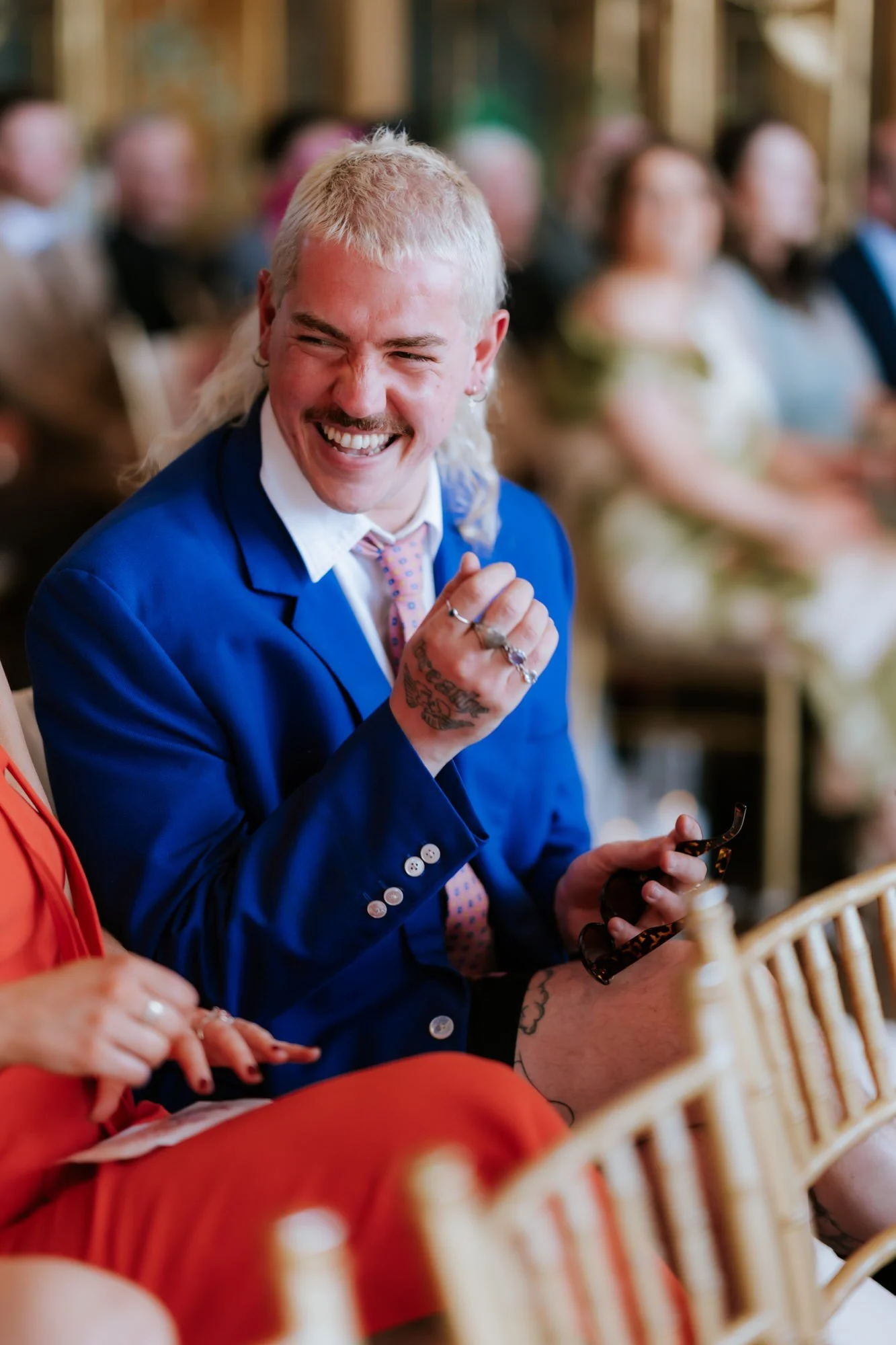 A guest in a bright blue suit laughing with friends.