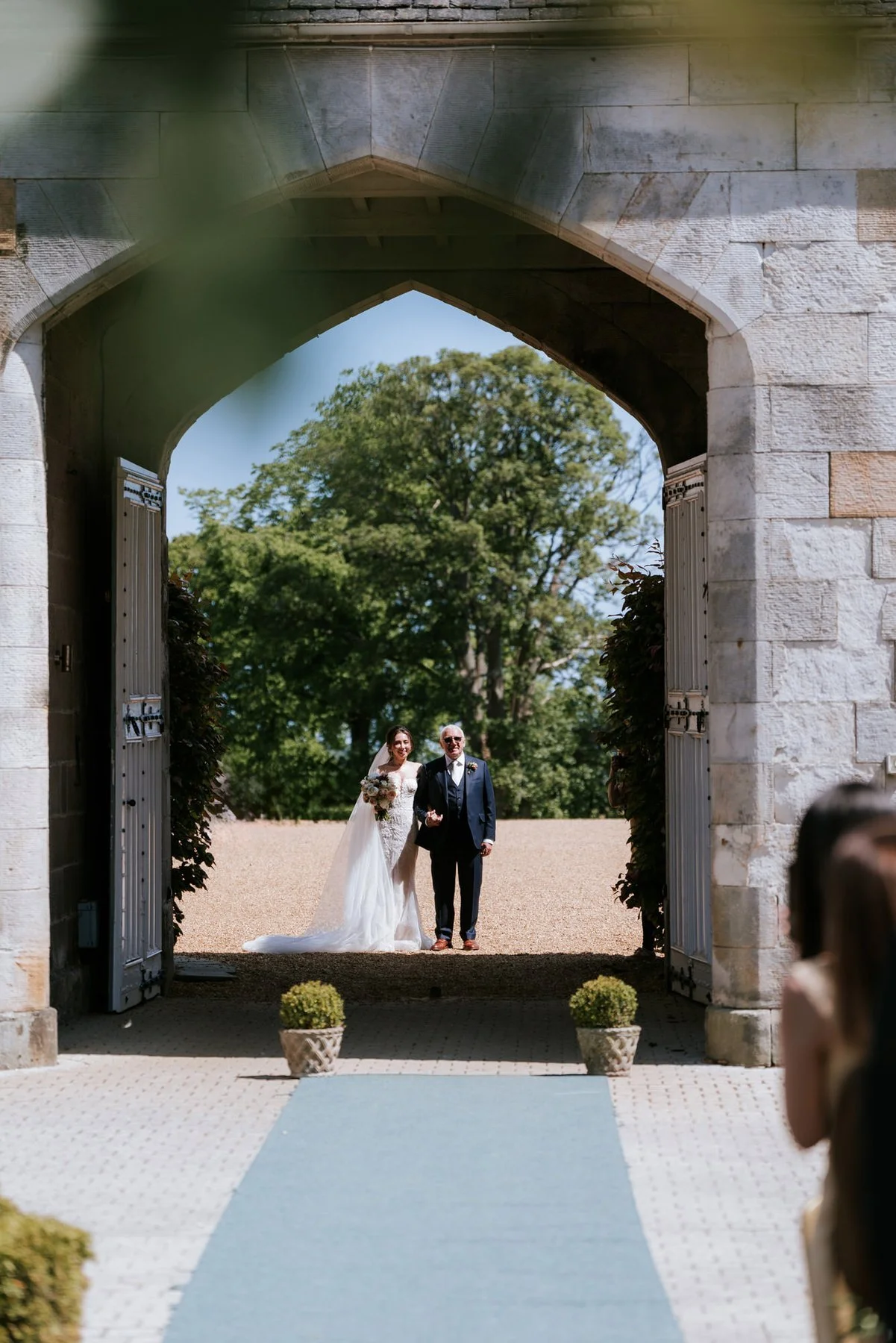 Kim and Kenneth walking together through the stone archway at Dundas Castle.