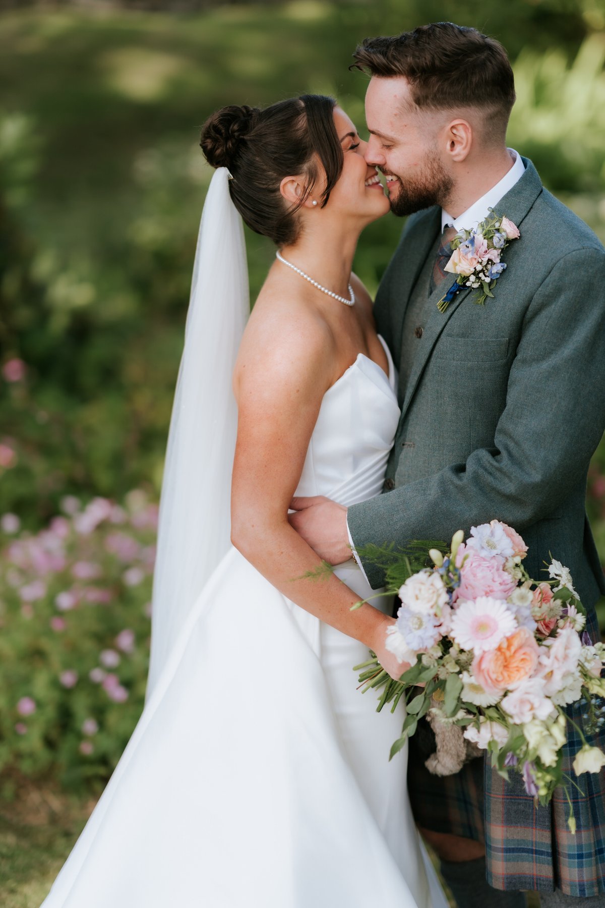 Lois and Dougie smiling nose to nose with her pastel bouquet between them.