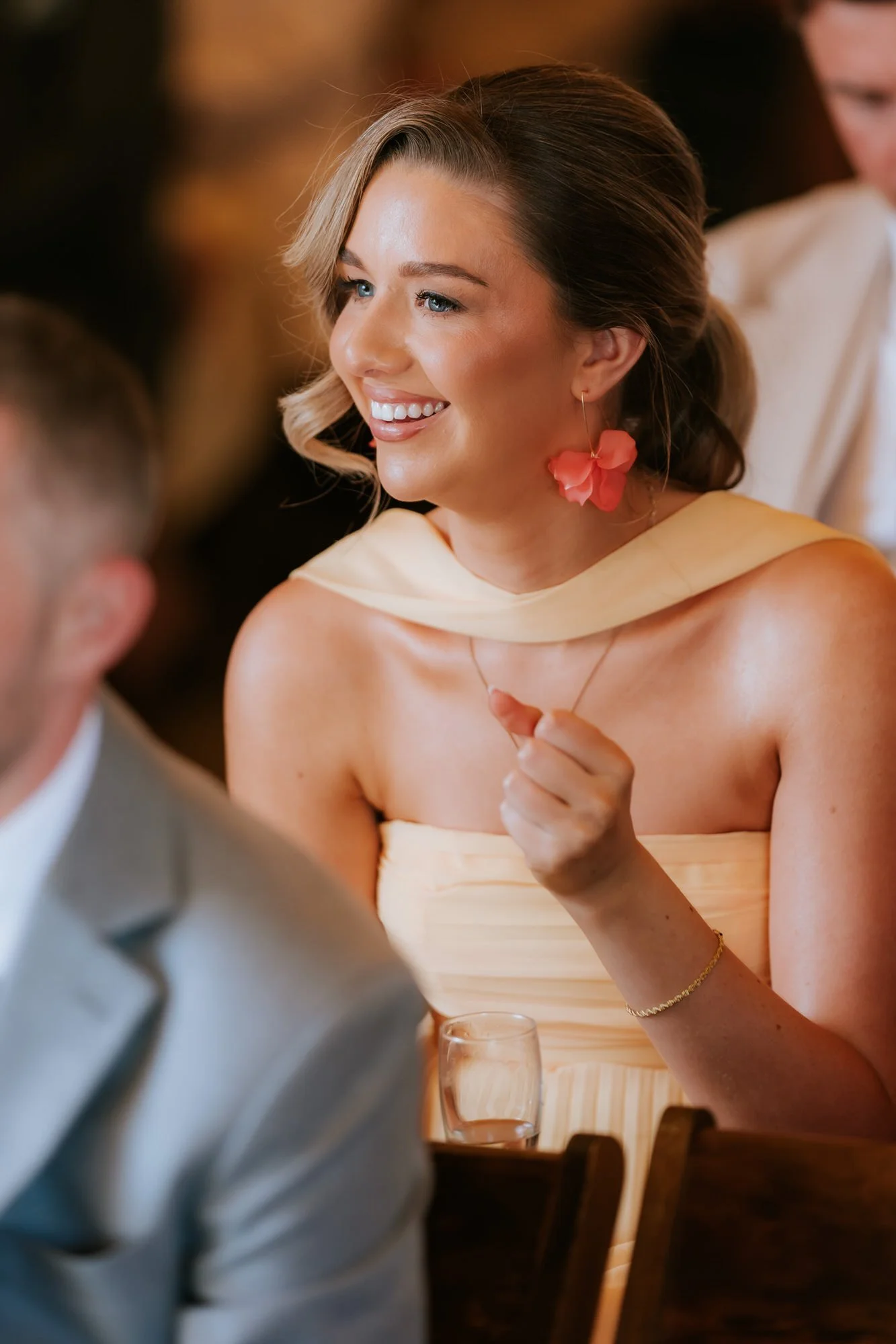 A wedding guest in yellow smiling during the ceremony